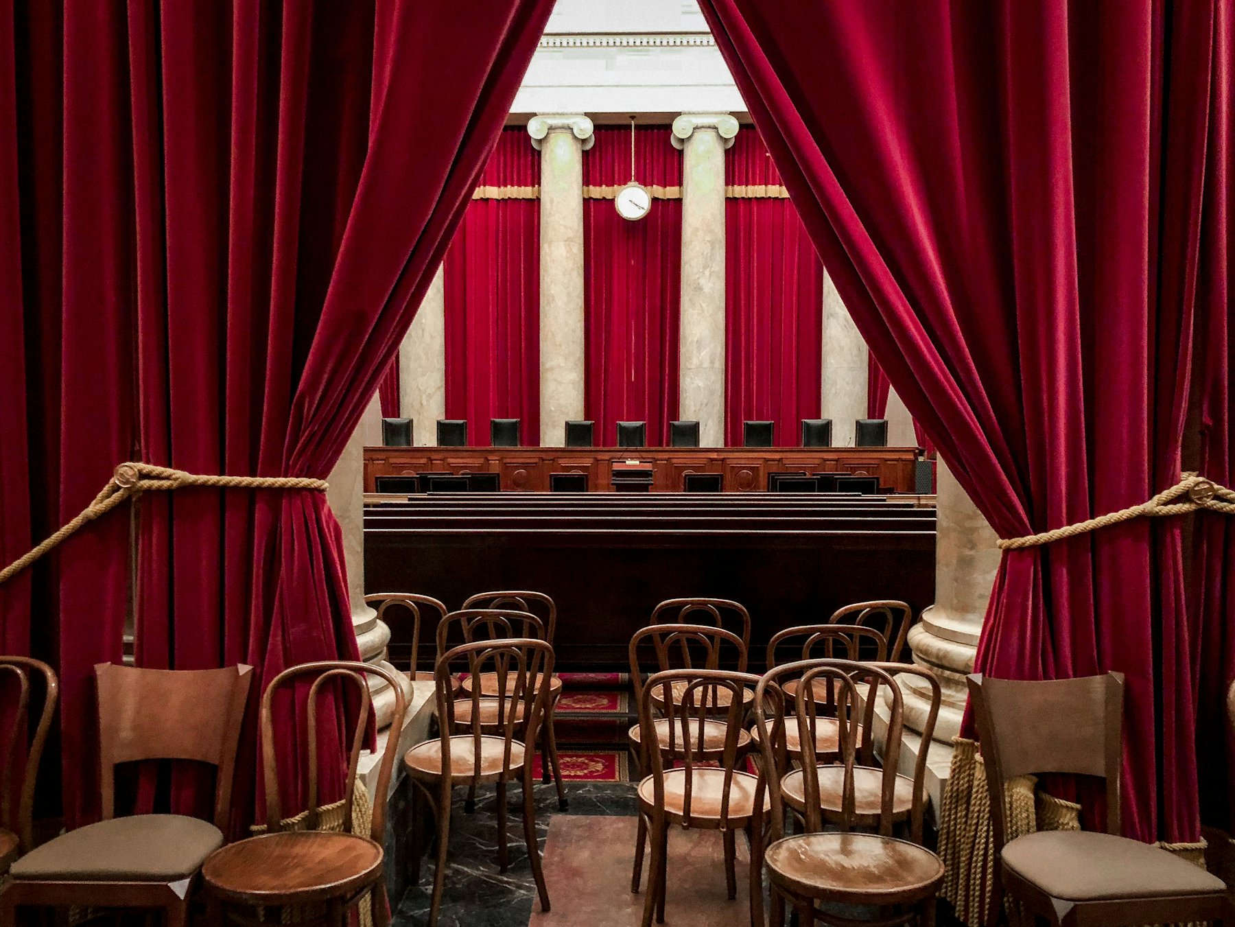 Wooden seating before a red curtain